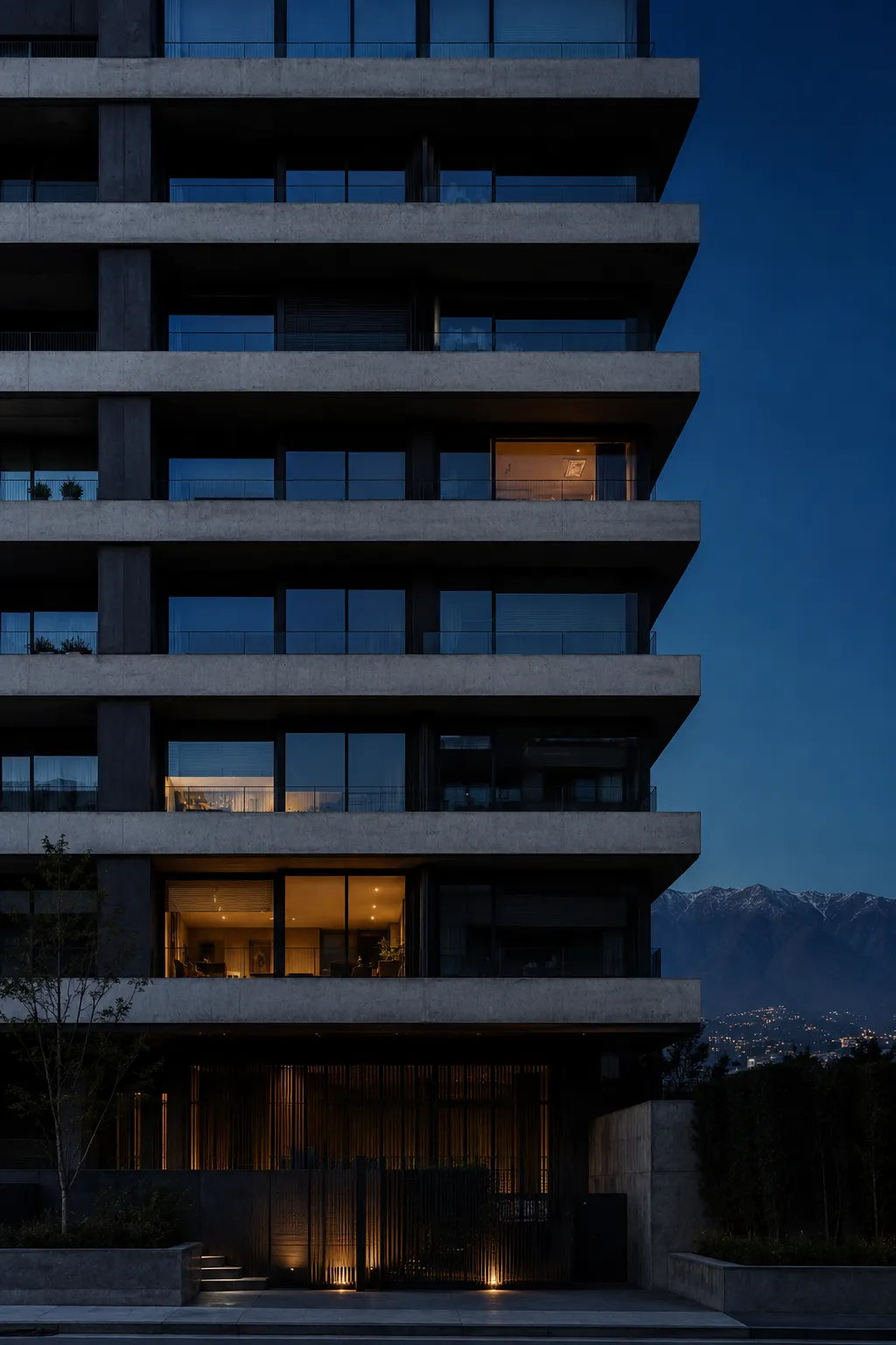 Edificio residencial contemporáneo en Santiago al anochecer, con la cordillera al fondo y algunos departamentos iluminados.